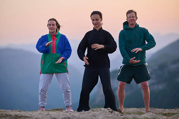 istock Group of people practicing Tai Chi outdoors at sunrise on mountain, performing slow meditative movements for balance, energy, health, and mindfulness in nature 2236211908