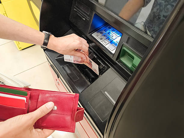 istock woman's hand puts a bill into a black atm 2236215250