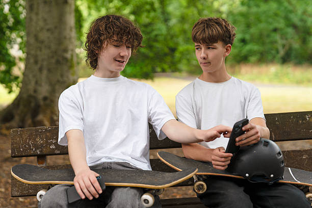 istock Friends enjoying a sunny day at the park while discussing skateboarding tricks and checking their phones 2236216634