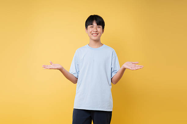 istock Smiling boy gestures with open hands Youthful expression on a vibrant yellow background 2236217782