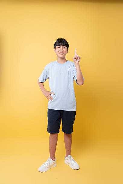 istock Enthusiastic boy pointing upwards suggesting an idea or concept set against a cheerful yellow backdrop 2236218368