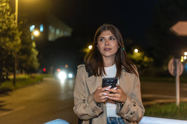 istock Woman using smartphone at night on city street 2236219073