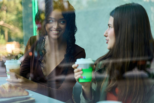 istock Two young women talking and drinking coffee in a cafe 2236222427
