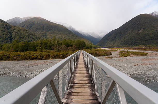 Looking down the length of Morrisons Footbridge, also known as Deception Bridge, which crosses the Otira River in the West Coast Region of New Zealand's South Island. The bridge is part of the Mingha - Deception Route in Arthur's Pass National Park.