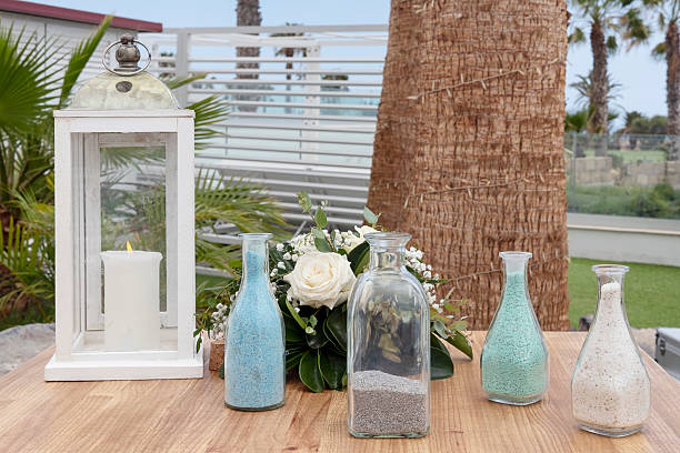 Two colorful hand-picked flower bouquets in small vases and a boho-style candle adorn a lovingly rustic table setting, elegantly garnished with scattered peanuts for a charming touch.