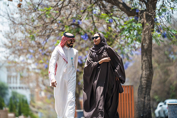 istock Arabic Couple Walking in Abha's Public Park with Jacaranda Trees 2236226068
