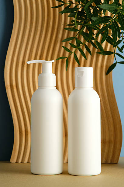 istock Two white bottles with pump and flip cap, wavy panel, green plant, blue background, minimalist cosmetic branding. 2236227873