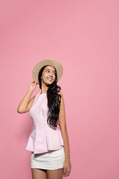 istock Young stylish woman with hat looking up on pink background with copy space 2236229308
