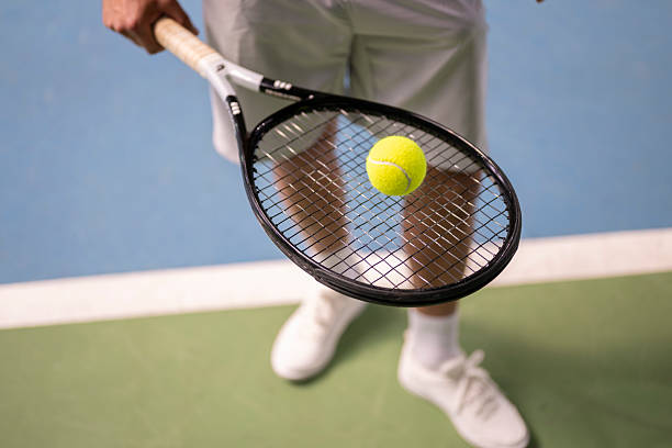 Tennis Player Balancing a Ball on Racket at Net