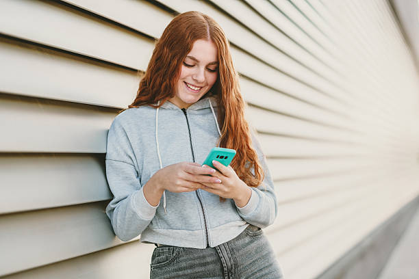 istock A young woman is texting on her smartphone while standing against a vibrant, modern background 2236237693
