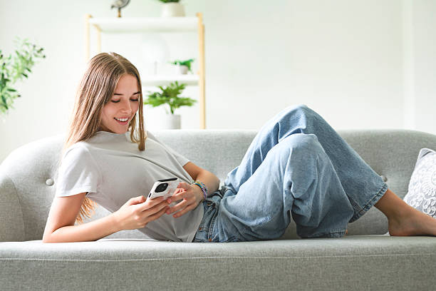 istock Handsome teenage girl sitting at home on the couch using cellphone 2236238708