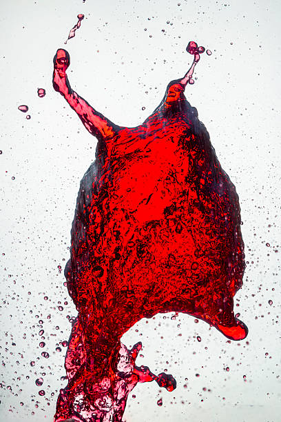 A splash of vivid red liquid caught mid-air, forming an abstract shape with droplets scattering around against a clean white background, frozen in motion with striking detail and texture.
