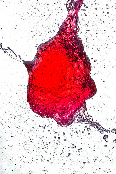 A splash of vivid red liquid caught mid-air, forming an abstract shape with droplets scattering around against a clean white background, frozen in motion with striking detail and texture.