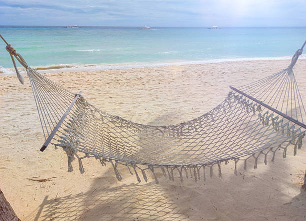 Relaxing hammock on sandy beach with turquoise water in tropical paradise, inviting relaxation at the shore