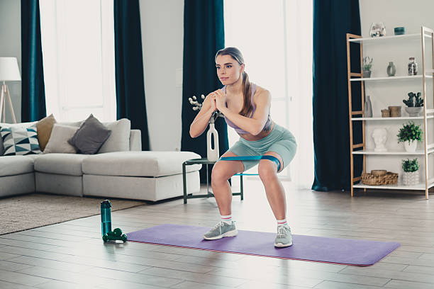 istock Young athletic woman performing squats with resistance band during home workout for strength and fitness training 2236250241