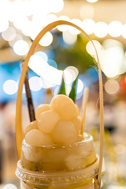 Glass of brown Thai longan drink with whole longan fruits on top