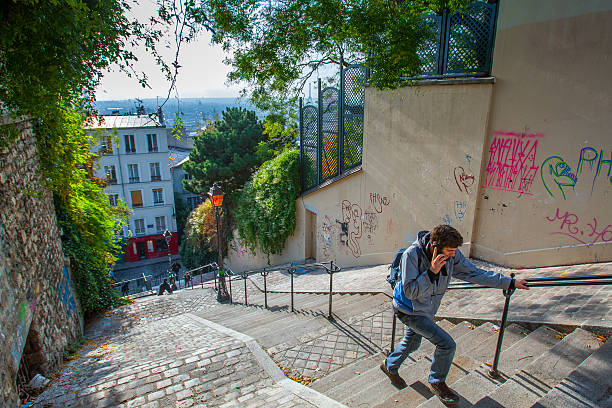 Paris, France  Nov 9, 2011: A man with a backpack on his shoulder talking on a mobile phone, walking up the stairs on Montmartre hill.