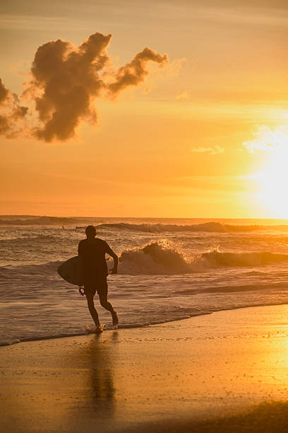 istock Surfer walking toward ocean waves during a golden sunset on the beach 2236251772