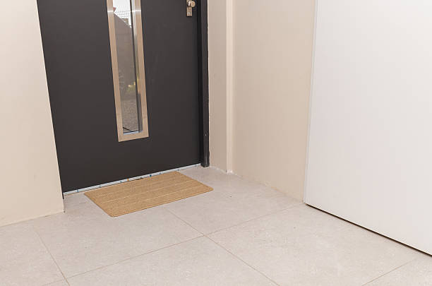 istock Entryway with black door and coir doormat on tile floor in modern interior 2236253577