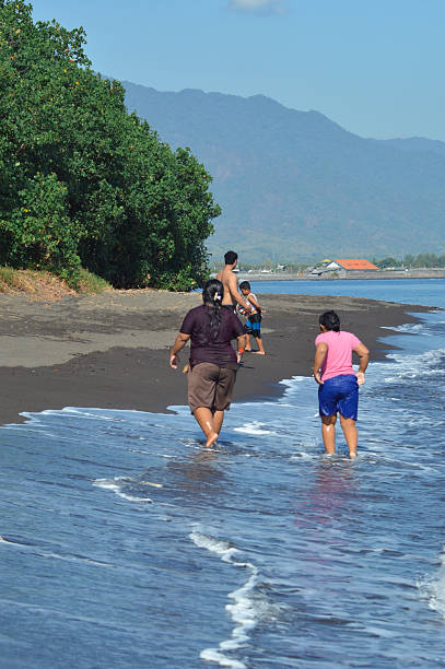 istock Family walking together along sandy shoreline with waves 2236255730