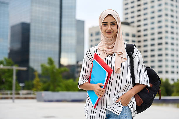 istock Muslim female student carrying backpack and folders on campus 2236256101