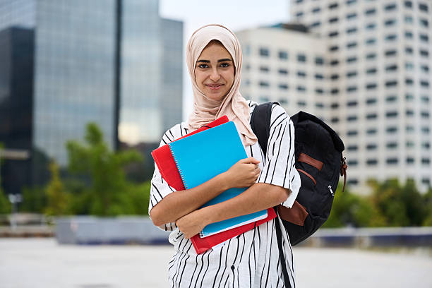 istock Muslim female student carrying books and backpack smiling 2236256126