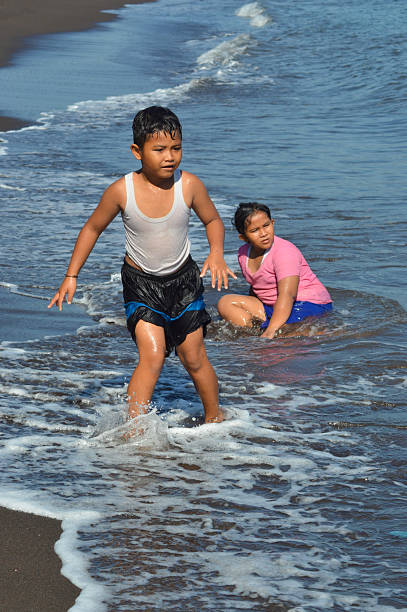 istock Young girl and boy enjoying playful seaside waves 2236256507