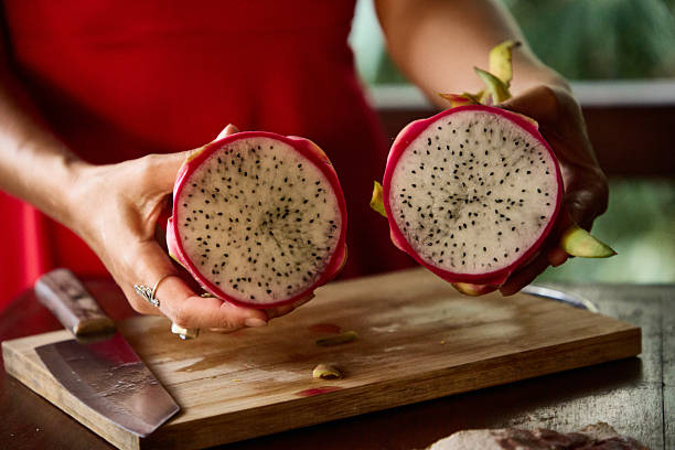 istock Closeup view of a sliced dragon fruit held by hands over a cutting board 2236257727
