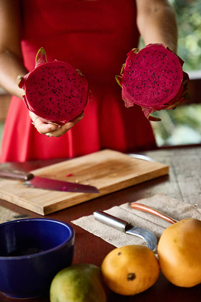 Person showcasing two vibrant dragon fruit halves with a table setup