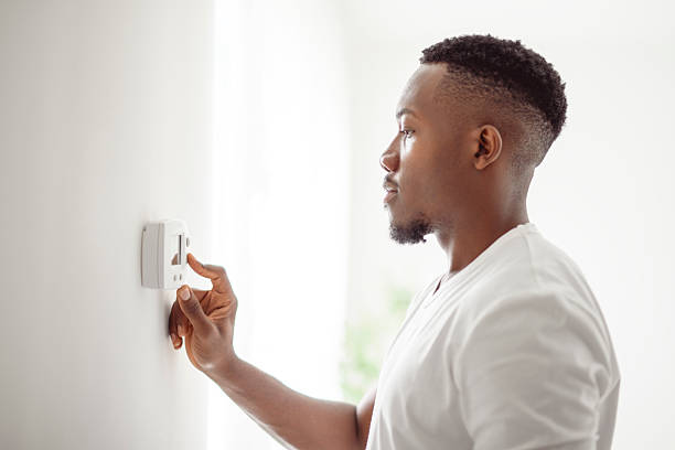 istock A Smiling black Man Adjusting Thermostat On Home Heating System 2236258174
