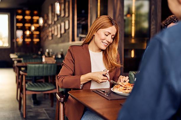 istock Woman Enjoying Pizza with Scissors in a Cozy Modern Restaurant Setting 2236258672