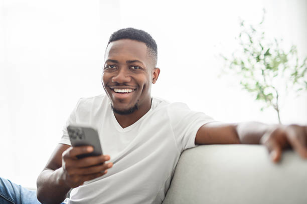 istock Black men wearing white shirt on sofa with holding cellphone 2236258861