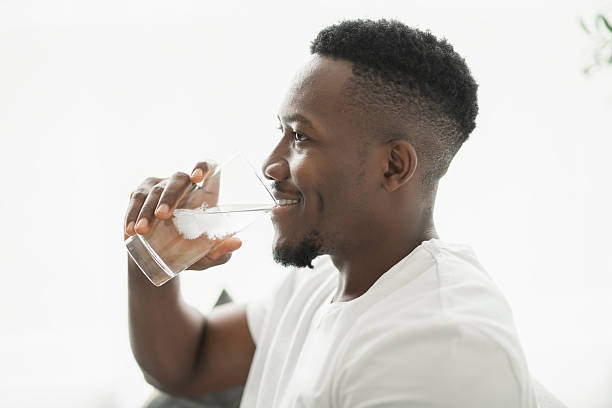 istock Black men wearing white shirt on sofa at home drink water 2236258940