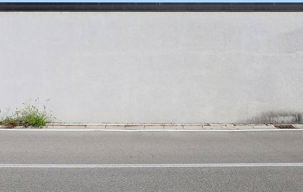 istock Light gray plaster wall at the roadside with street in front 2236259015
