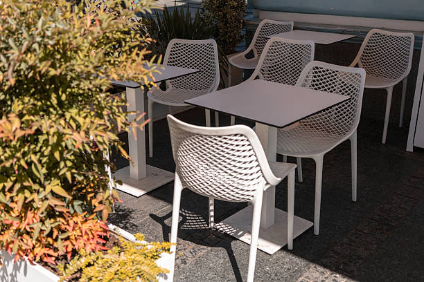 istock An empty street cafe or restaurant terrace with white tables and chairs surrounded by greenery, no people. 2236260253