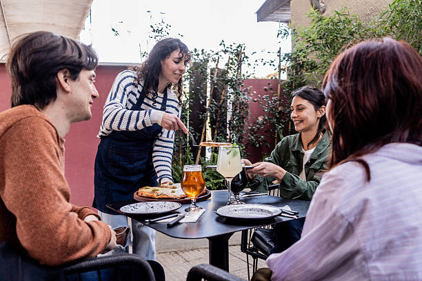 istock Waitress serving pizza to customers in a restaurant 2236264212
