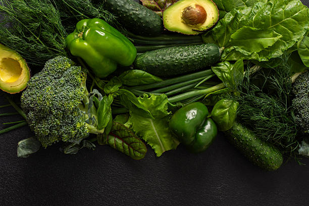 istock Various green vegetables such as broccoli, cucumbers, green peppers, and lettuce, fresh herbs like basil and dill, along with ripe avocado are artfully arranged on a dark background, healthy meal 2236265144