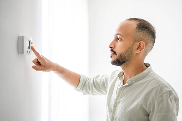 istock Hispanic Man adjusting room temperature with electronic thermostat at home 2236266655