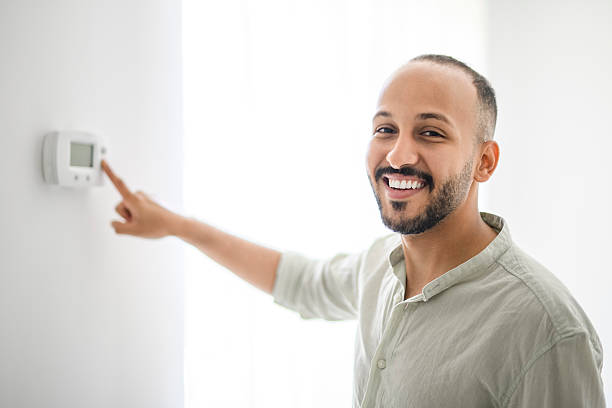 istock Hispanic Man adjusting room temperature with electronic thermostat at home 2236266659