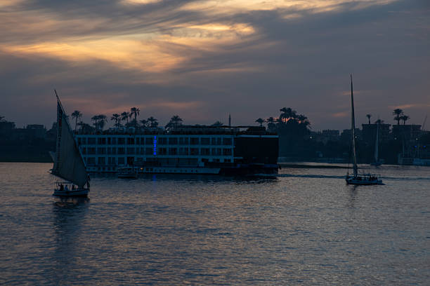 Luxor, Egypt - Feb 4, 2025: A beautiful sunset over the River Nile with a tourist cruise boat and dhow.