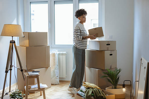 istock Young woman organizing boxes while moving into a bright living room space 2236272186