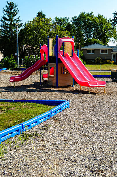 istock Red slides on a playground in a residential area under a blue summer sky, 2236272811