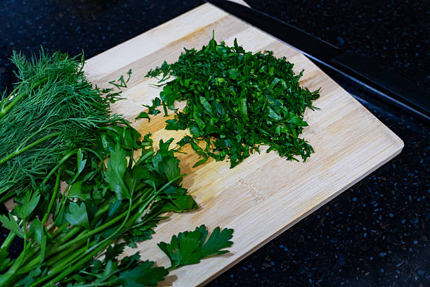 Close-up of woman cutting cilantro with a kitchen knife at home