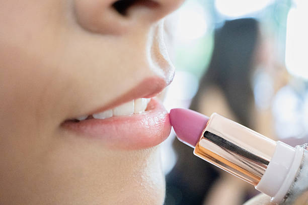 young woman applying pink lipstick