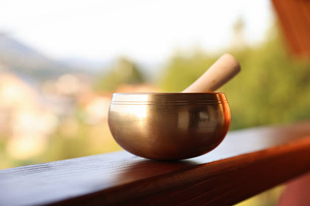 Tibetan singing bowl with mallet on handrail outdoors, closeup