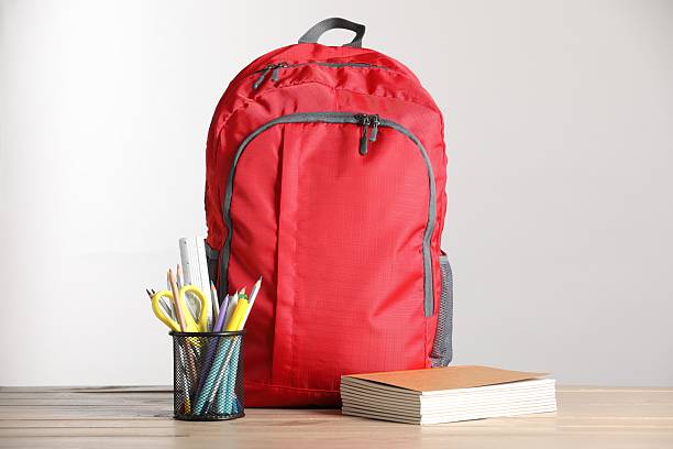 istock Red backpack and different stationery on wooden table against light background 2236279980