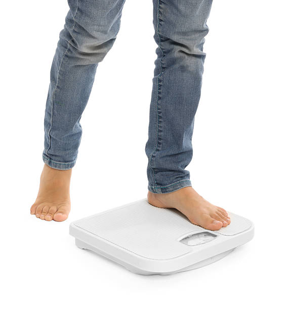 istock Little boy standing on scales against white background, closeup 2236280628