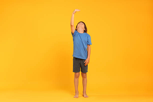 istock Little boy measuring his height on orange background 2236280685