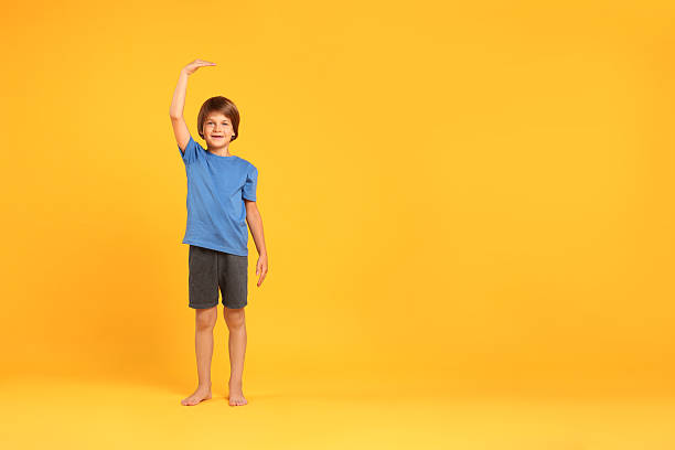 istock Little boy measuring his height on orange background, space for text 2236280709