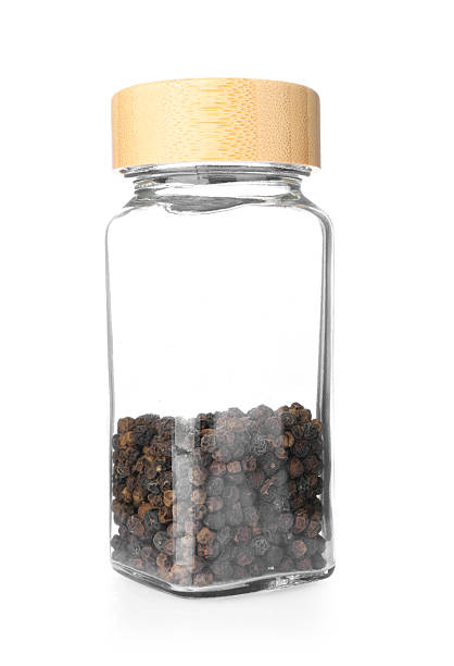 Peppercorns in glass jar isolated on white. Aromatic spice